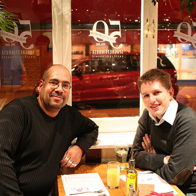 Mike Little and Matt Mullenweg smiling facing the camera in a restaurant booth